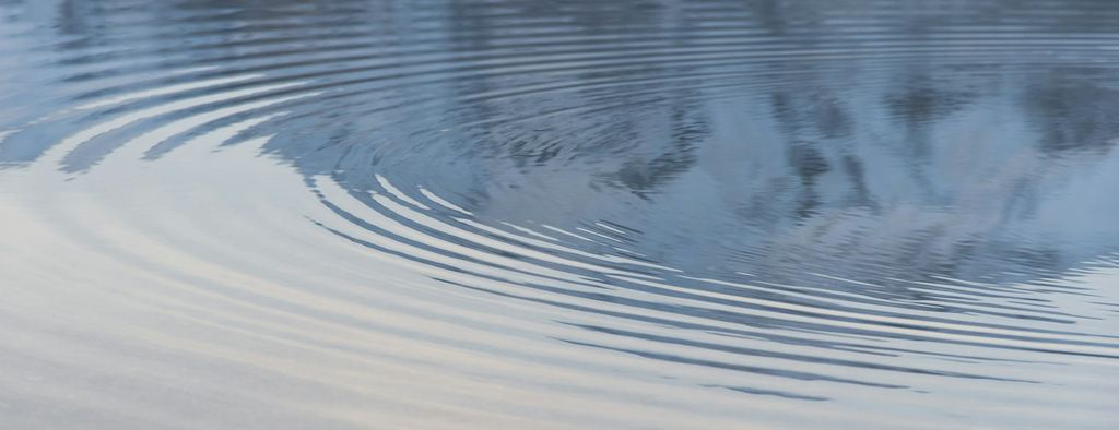 Concentric ripples spreading across calm blue water